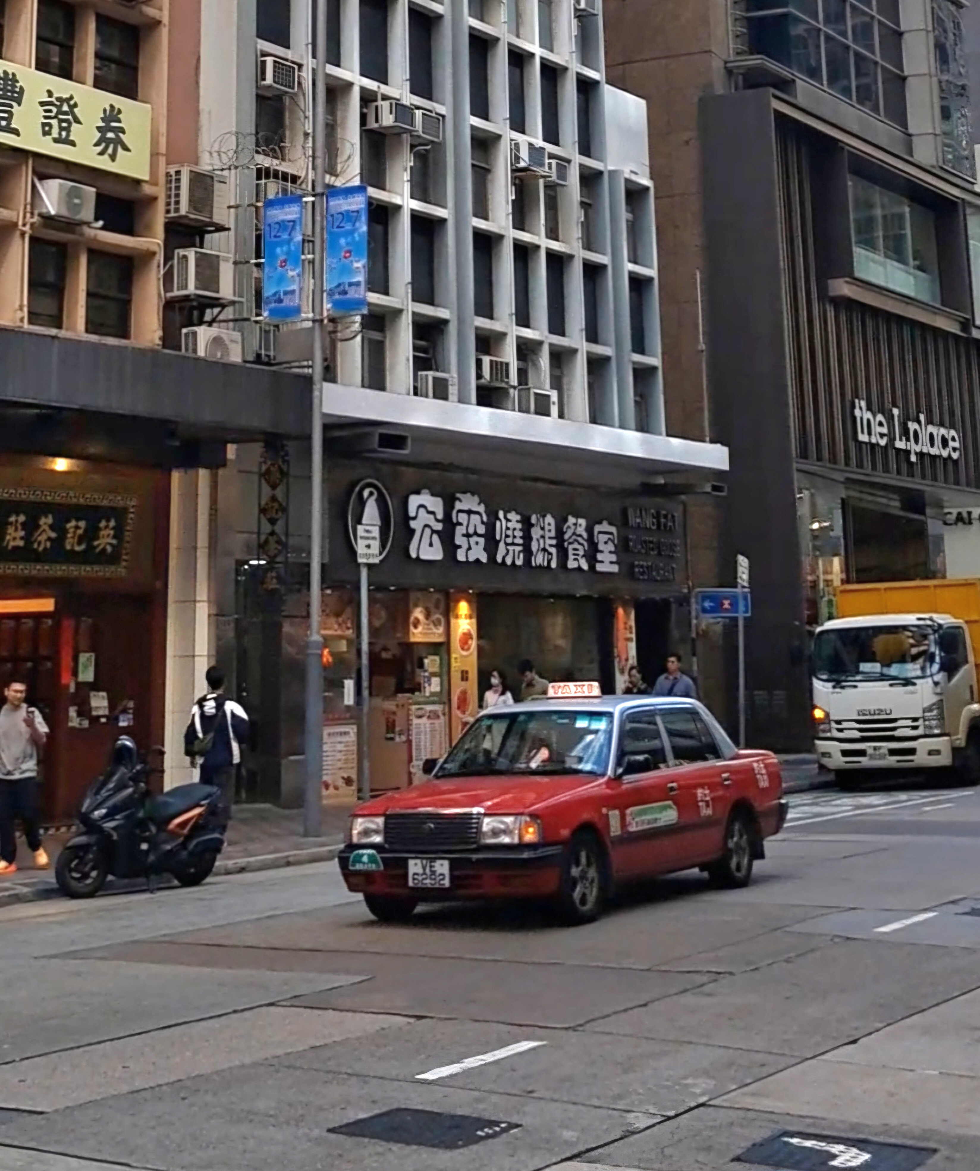 A red Hong Kong taxi driving on a street in Hong Kong Island